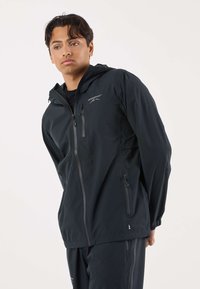 Black lightweight rain jacket with a hood, featuring zippered front, two side pockets, and a logo on the left chest, smooth texture.