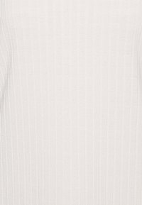 Tejido blanco acanalado que presenta un patrón texturizado con líneas verticales, creando una apariencia sutil y uniforme. Material suave y ligero.