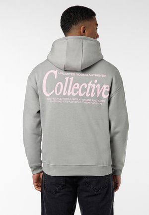 Grauer Kapuzenpullover mit pinkem Text auf der Rückseite. Der Text enthält "Collective" und weitere Branding-Details. Der Stoff sieht weich und strukturiert aus.