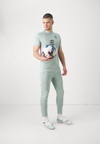 Lichtgroene sportoutfit met korte mouwen, textuurstof, slim fit broeken, met een voetbal met een geometrisch patroon.