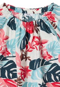 Escote elástico de una prenda con estampado floral tropical en azul, rojo, rosa y marrón; la etiqueta visible de la marca dice "CECIL."