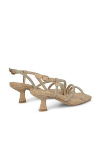 Sandalias de tacón beige con acabado de ante, que presentan tiras de rhinestones plateados y un tacón bloque para mayor estabilidad. Cierre con hebilla en el tobillo.
