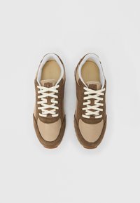 Smeđe antilop tenisice i bež mrežasti dijelovi s bijelim vezicama, podstavljenim ovratnikom i teksturiranim gumenim potplatom. Minimalistički dizajn, ravno vezanje.