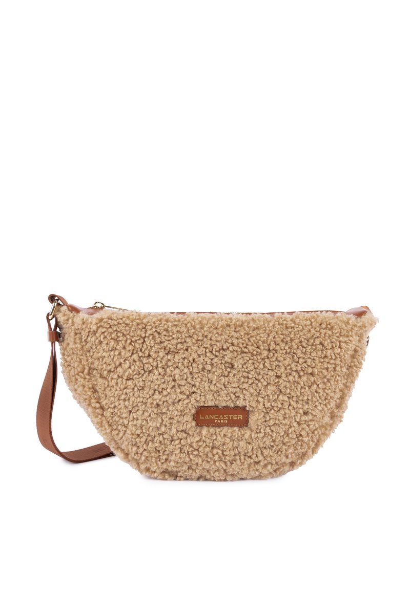 Beige faux fur crossbody bag with a rounded shape, brown leather strap, and a gold zipper. Features a branded leather patch on the front.
