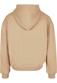 Felpa beige con una finitura morbida e testurizzata; presenta un cappuccio con cordini, polsini a coste e un design con orlo cropped.
