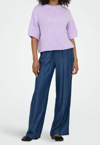 Maglione lilac lavorato a maglia con maniche corte, abbinato a pantaloni in denim morbidi. Le scarpe nere completano l'outfit. Design semplice e rilassato.