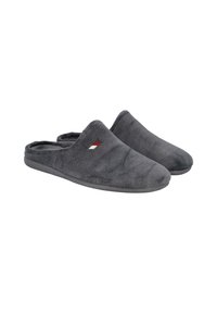 Par de pantuflas de felpa gris sin sujeción, con suelas suaves y un pequeño logo bordado en rojo y blanco en la parte superior.