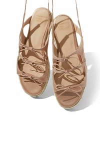 Bež espadrile sandale s zatvorenim petama, otvorenim prstima, višestrukim križnim trakama s mašnama i platformom od teksturirane užadi.