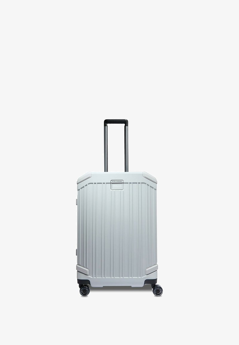 Maleta de carcasa dura con un exterior texturizado plateado que presenta ranuras verticales, un asa retráctil negra y cuatro ruedas para facilitar la movilidad.