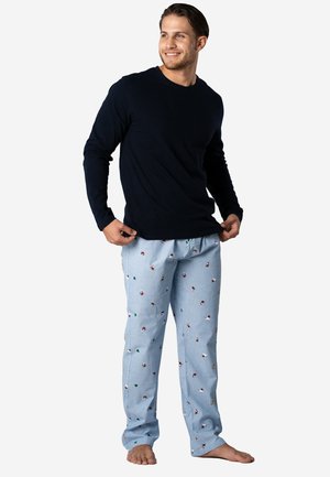 Donkerblauwe lange mouwshirt gecombineerd met lichtblauwe broek met een patroon van kleine kleurrijke figuren en bomen. Het materiaal lijkt zacht en heeft een relaxte pasvorm.