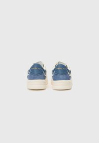 Blå ruskinnssneakers med kremfargede detaljer, med en teksturert overdel, polstret krage og en gullfarget "REPLAY"-logo på hælen.