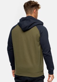 Sudadera con capucha de cuerpo verde y mangas de color marino. Presenta un acabado texturizado y un dobladillo ajustado. Incluye una capucha suave y puños acanalados.