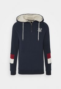 Marineblauwe hoodie met halve rits, crèmekleurige fleece-voering in de kap, witte trekkoorden, een voorzak en rode en witte strepen op de mouwen.