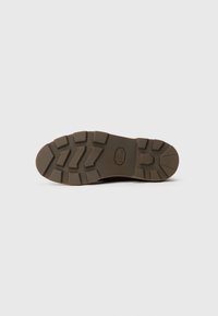 Suela de zapato con un diseño de goma marrón y rugoso. Presenta patrones de relieve profundos para mayor tracción, bordes suaves y una ligera curvatura en la punta.