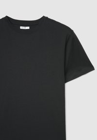 T-shirt nera in cotone con scollo tondo, maniche corte e texture liscia. Presenta un'etichetta con la scritta "CALLIOPE" nella zona del collo.