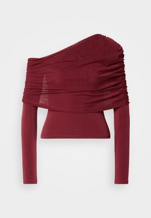 Haut bourgogne à manches longues avec une conception asymétrique sur une épaule ; présente un tissu froncé et une silhouette ajustée. Texture lisse et matériau extensible.