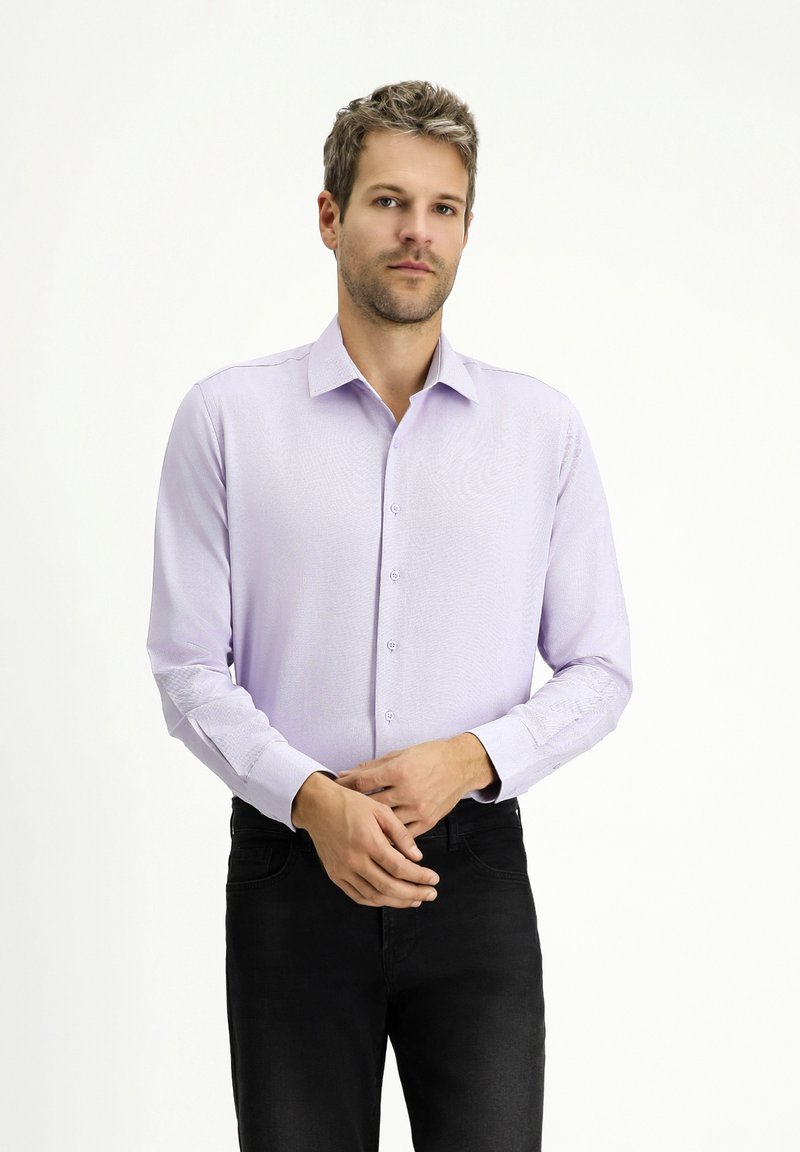 Camicia a maniche lunghe in lavanda con un motivo sottile, chiusura frontale con bottoni e colletto a punta. Abbinata a jeans neri.