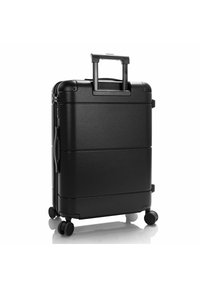 Black hard-shell suitcase with a retractable handle, four wheels, smooth texture, and minimalist design. Zipper closure with accent lines.