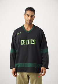 Čierny atletický dres s zelenými akcentmi a logom "CELTICS". Má V-krčný dizajn a dlhé rukávy, vyrobený z priedušného materiálu.
