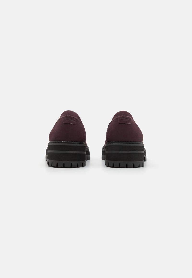 Burgunderfarbene Wildlederschuhe mit runder Form, flachen schwarzen Gummisohlen und TOMS-Logo auf der Ferse. Strukturiert mit mattem Finish.