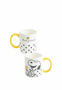Tazza di ceramica bianca con manico giallo, pois neri e illustrazioni di Snoopy e un uccello. Il testo dice "migliore amico" con un cuore giallo.