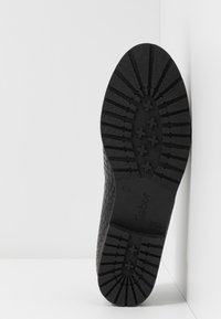 Semelle de chaussure noire avec un motif texturé en nid d'abeille et des rainures pour une meilleure adhérence. Estampillée "Gabor" et taille "4½". Design plat standard.