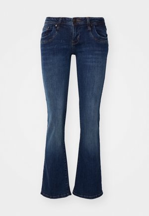 Tumesinine denimist laienevad teksad keskmise kõrgusega taljega, viie taskuga ning peente õmblusdetailidega õmblustes ja tasku servades.