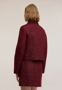 Burgundská tvídová sako s krátkým střihem, límcem, texturovaným povrchem a dlouhými rukávy, spárované s odpovídajícími mini sukni.