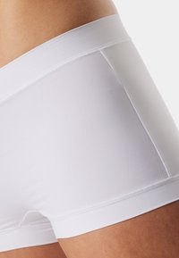 Białe bokserki z bawełnianej mieszanki z miękkim pasem, gładką fakturą i dopasowanym krojem, z minimalnymi przeszyciami wzdłuż krawędzi.