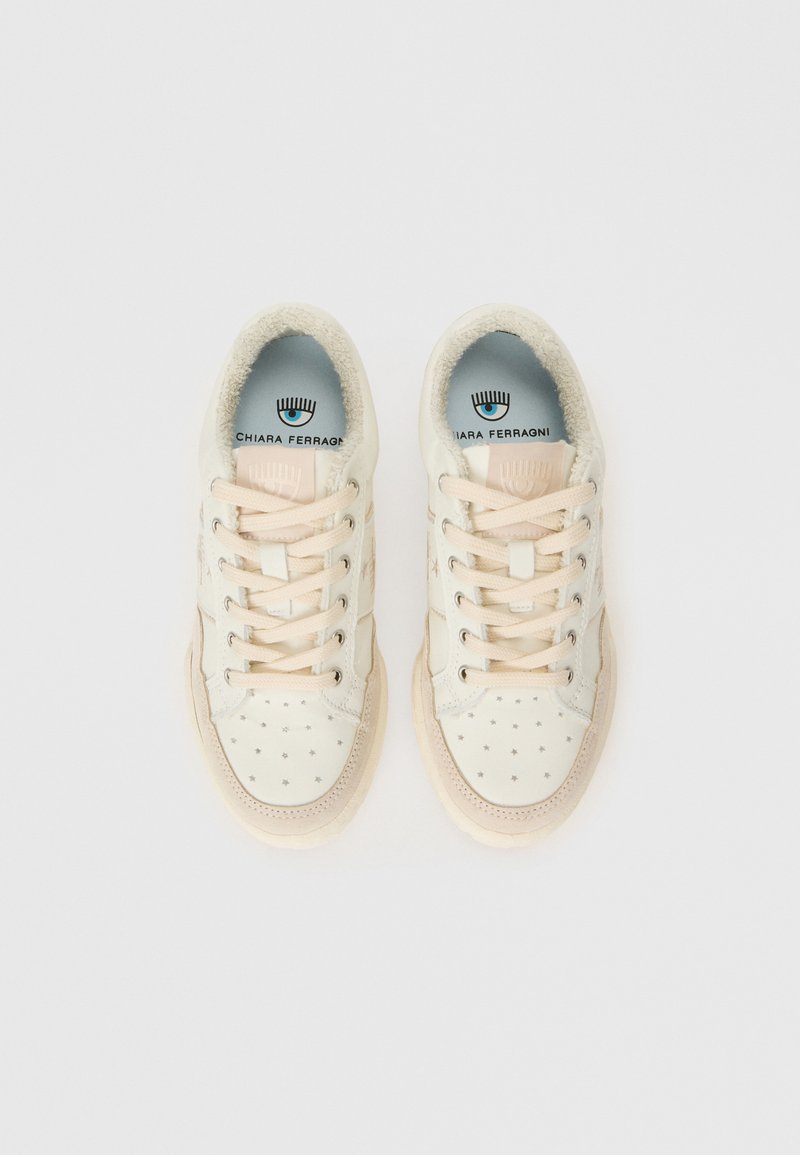 Zapatillas hechas de cuero color crema con patrones de estrellas, cordones color beige claro y forro suave; presenta el logotipo de la marca en la plantilla.
