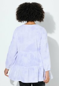 Lichtpaarse, lange mouwen peplum top gemaakt van gestructureerde stof met een geplooid onderste gedeelte en een zachte tie-dye print. Gladde halslijn.