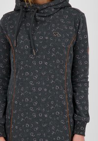 Czarna szara sukienka dresowa z kapturem, z wzorem w jasnoróżowe kółka, sznurkami do regulacji oraz brązowymi akcentami wzdłuż szwów.