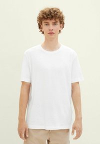 White cotton t-shirt with a round neckline and short sleeves. Relaxed fit with rolled sleeve cuffs and subtle side seam detail.