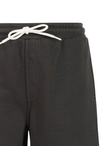 Close-up van zwarte joggingbroek met elastische tailleband en wit trekkoord knoop in een strik, met zichtbare stiksels van het voorvak.
