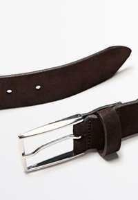 Tmavě hnědý semišový pásek se stříbrnou kovovou přezkou obdélníkového tvaru, který má pět děr pro nastavení velikosti a jemné kožené šití.