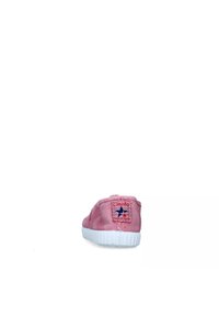 Sneaker in tela rosa con suola in gomma bianca, caratterizzata da un'etichetta cucita con accenti rossi e blu sul tallone. Texture liscia, design a profilo basso.