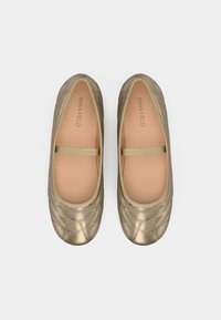 Ballerines dorées avec un design matelassé, présentant un dessus doux au toucher, une bride élastique et une doublure intérieure beige. Marque : Anna Field.