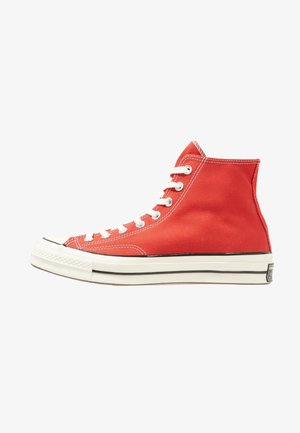Sneaker alta in tela rossa con lacci bianchi, suola in gomma bianca e dettaglio a striscia nera, mostrata di lato su sfondo bianco.