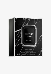 Boîte en noir et blanc pour Guess Uomo Eau de Toilette, ornée d'un motif en marbre et d'une étiquette noire bien visible avec des accents et des textes argentés.