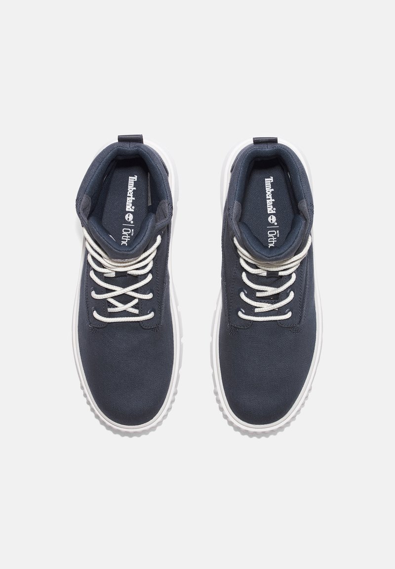 Dunkelblaue Leinenschuhe mit weißen Schnürsenkeln und einer weißen Gummisohle, ausgestattet mit einem gepolsterten Kragen und "Timberland"-Markierung auf der Innensohle.