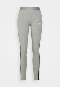 Leggings grises hechos de un material suave, con una amplia cinturilla gris y rayas laterales negras. Pequeño logo blanco de Adidas en el muslo izquierdo.
