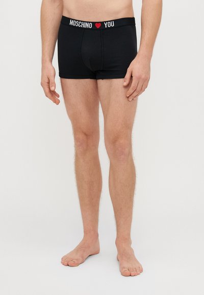Boxer briefs pretos com uma banda elástica branca apresentando o texto "MOSCHINO ❤️ YOU". Tecido suave com um design ajustado e pernas curtas.