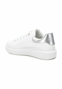 Zapatilla blanca con parte superior de cuero liso, punta redonda, acento plateado en el talón y suela de goma blanca gruesa. Cuenta con seis ojetes para los cordones.
