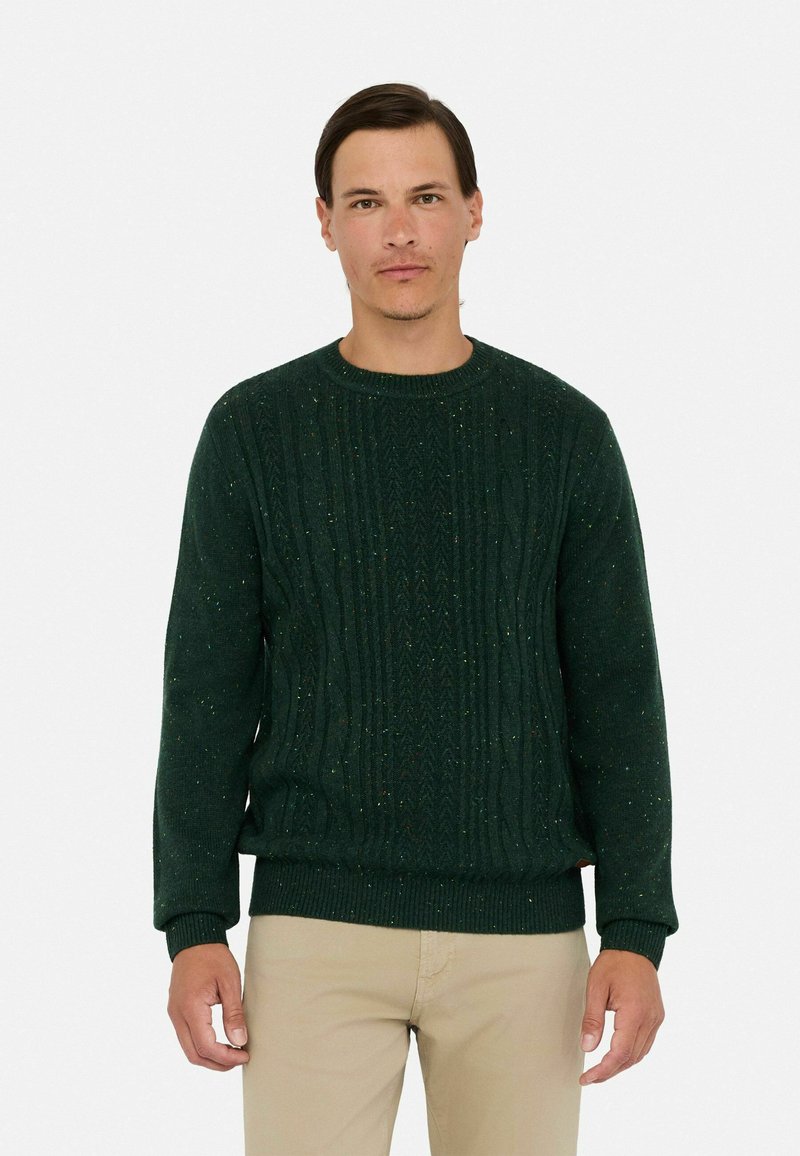 Dunkelgrüner Strickpullover mit strukturiertem Zopfmuster, rundem Halsauschnitt, gerippten Bündchen und Saum. Dezente, mehrfarbige Punkte überall.