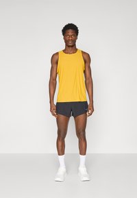 Yellow sleeveless athletic shirt paired with dark shorts; athletic shoes and white socks. Simple design with minimal accents, lightweight fabric.