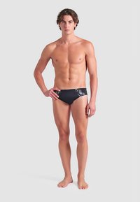 Svarta badbyxor med en accent av geometriskt grått mönster, med en slät textur. Designen är åtsittande och minimalistisk.