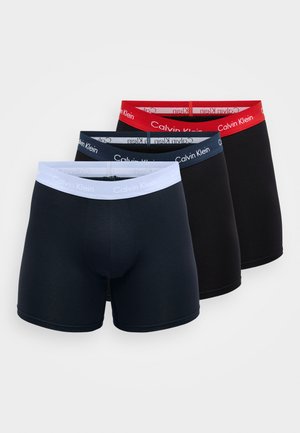 Drei Paar Herren-Boxershorts in Schwarz, Marineblau und Grau. Jede setzt auf einen elastischen, markenbezogenen Gürtel in kontrastierenden Farben.