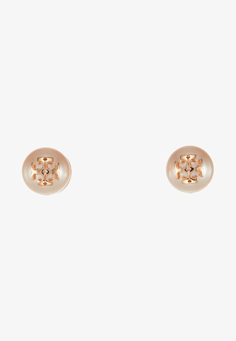 Boucles d'oreilles en métal doré avec une surface brillante, présentant des motifs floraux découpés au centre. Forme ronde, texture lisse.