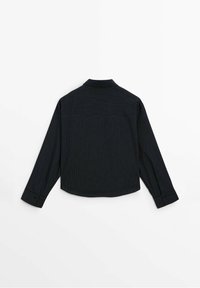 Chemise noire à manches longues avec de fines rayures blanches, vue de dos, avec un empiècement et des poignets boutonnés.