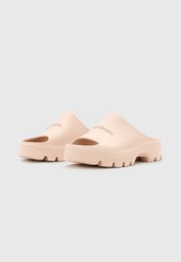 Ljust rosa formade slip-on sandaler med öppen tå, tjock sula och texturerad botten för grepp. Varumärket präglat på ovandelen.